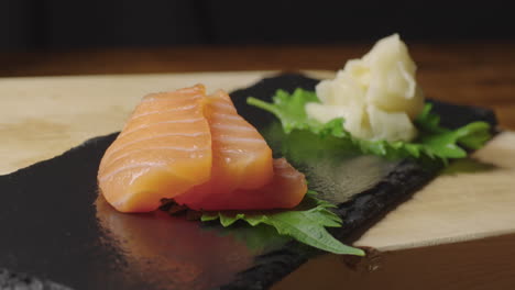 raw salmon and tuna sashimi being placed on slate tray