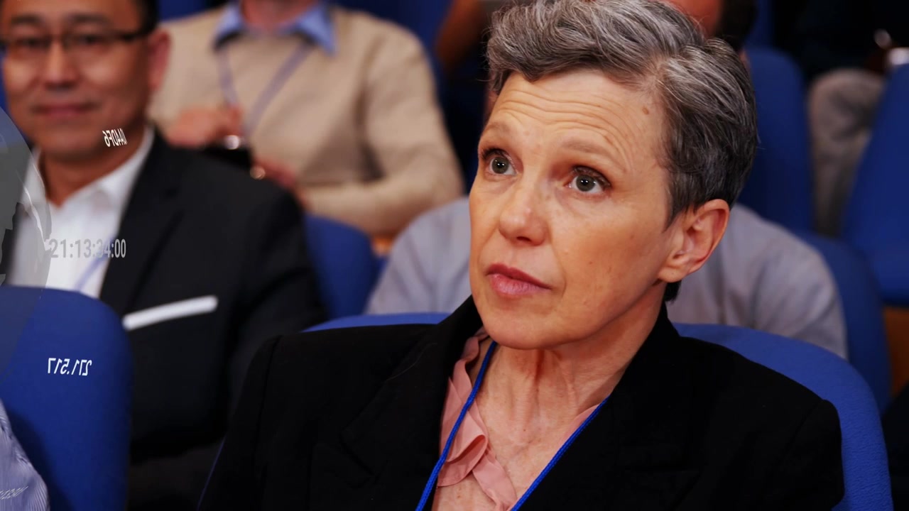 Woman taking notes during tech talk projecting rotating globe time overlays drifting over seats