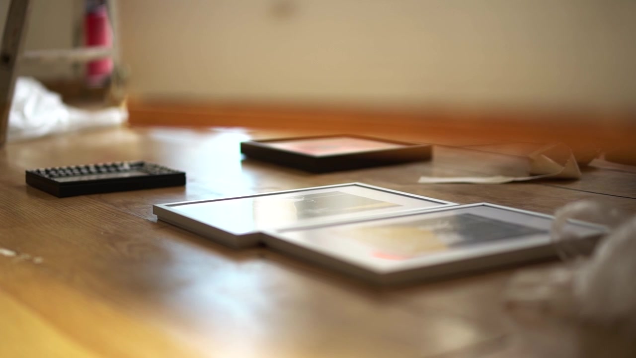 Hand held close up picture frames lying on the floor as someone walks past.