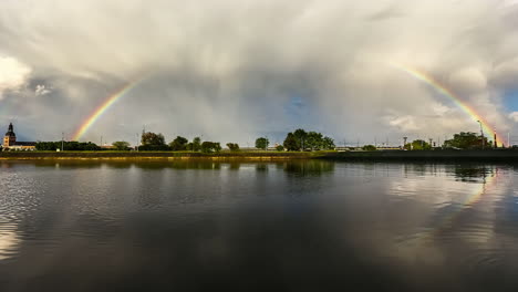 toma de lapso de tiempo del hermoso arco iris sobre la ciudad de riga y el río daugava en movimiento - nubes volando en el cielo azul