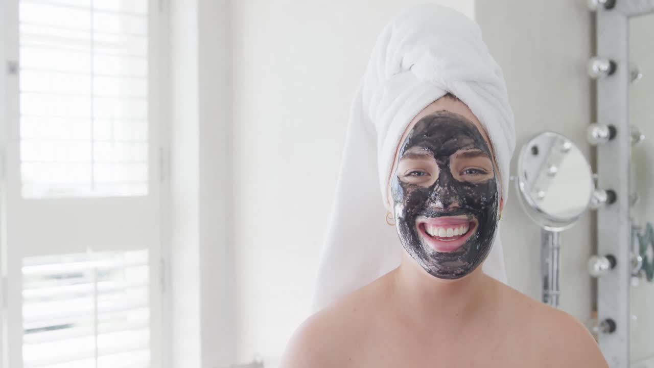 Porträt einer glücklichen kaukasischen kurvigen Frau mit einem Handtuch auf dem Kopf und Maske in Zeitlupe.