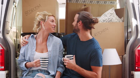 pareja tomando un descanso en la parte trasera del camión de mudanzas el día de la mudanza