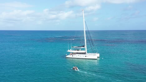 tourists ferried to catamaran with inflatable boat, azure blue caribbean