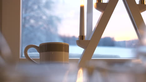 hot cup of tea near christmas decorations and window with winter landscape view