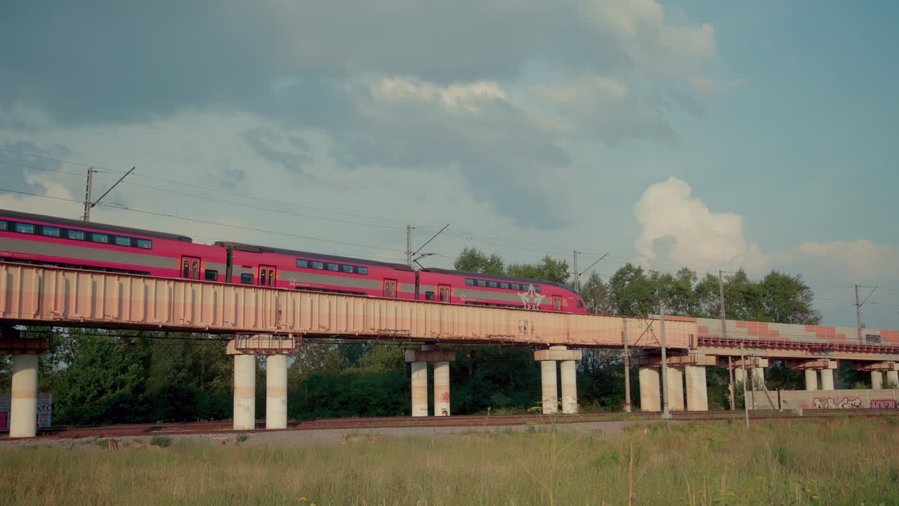Treno rosso a due piani che attraversa il ponte ferroviario.