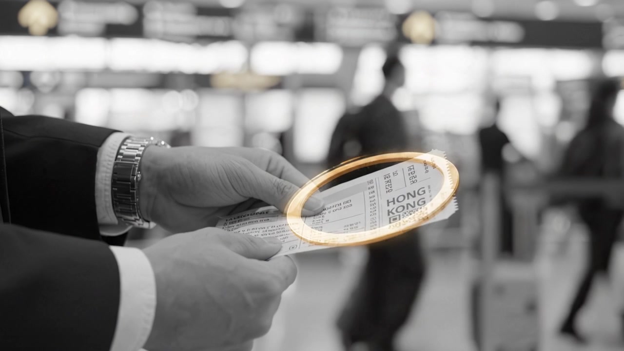 A Close-Up View of an Individual's Hands Holding a Ticket with Destination 'Hong Kong' in a Busy Airport Check-In Area