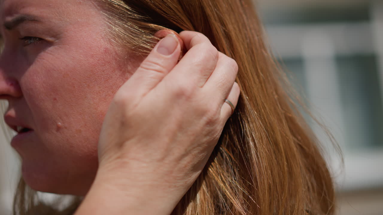 Close up of worried woman adjusting hair under bright sunlight, revealing emotional tension and introspection, natural light highlights texture of hair and subtle facial lines