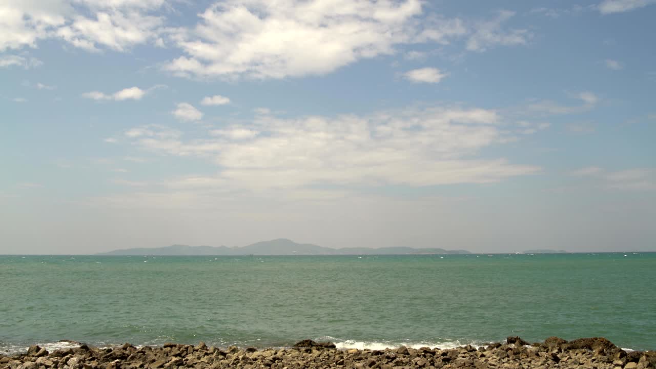 풍경. 구름이 가득한 하늘. 지평선. 산의 배경에 있는 바다. 돌로 된 해변