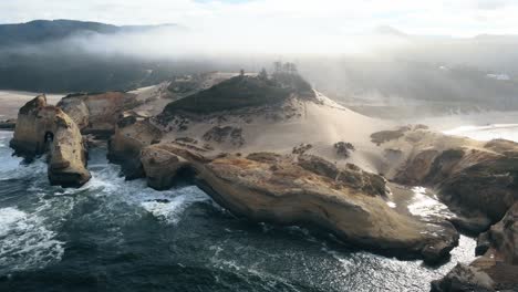 Aerial-establishing-shot-of-waves-crashing-at-Cape-Kiwanda-with-low-lying-clouds