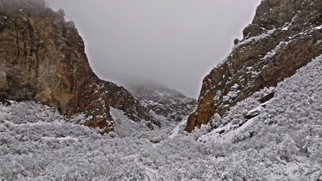 La-Plataforma-Rodante-Aérea-Cinematográfica-Se-Inclina-Hacia-Arriba-Para-Revelar-épicos-Acantilados-De-Roca-De-Cuarzo-Marrón-Cubiertos-De-Nieve,-Rock-Canyon-Utah