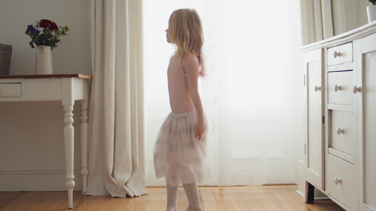 hermosa niña bailando juguetón fingiendo ser bailarina divertido niño divirtiéndose jugando a vestirse con traje de ballet con alas de hada en casa 4k