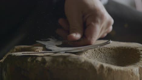 close up shot of blacksmith hand beating iron foil with hammer at workshop