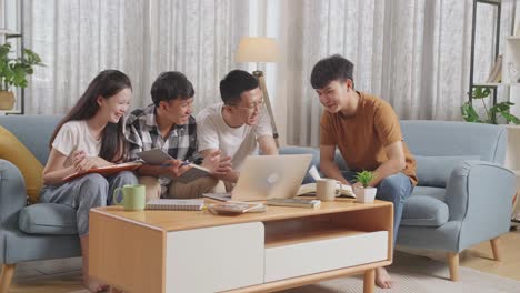 asian teen group studying at home. break time, watching funny video, laughing at joke, using laptop, working on online project