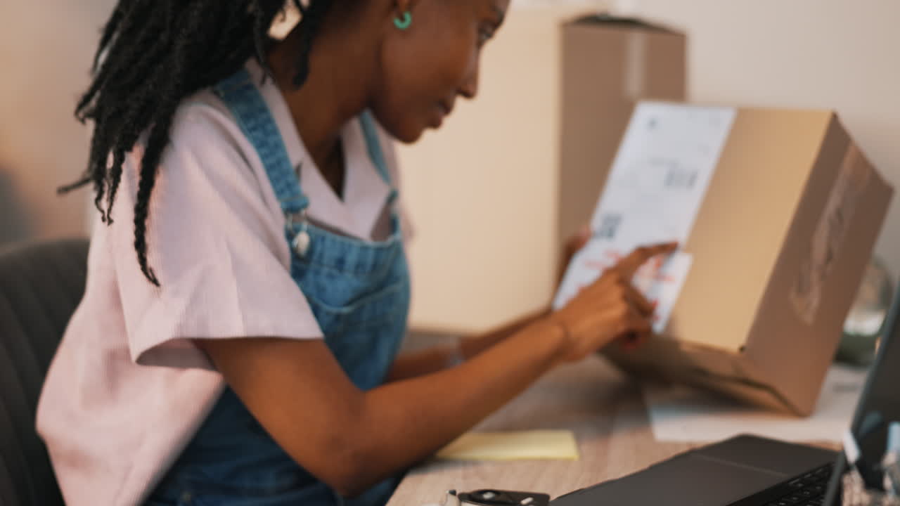 portátil, caja y mujer negra escribiendo en el envío