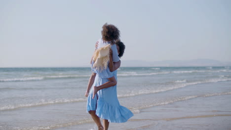 happy mother catching her daughter, lifting up and spinning around at the seashore, while the girl laughing