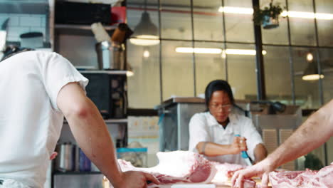 tres carniceros preparando carne en una carnicería