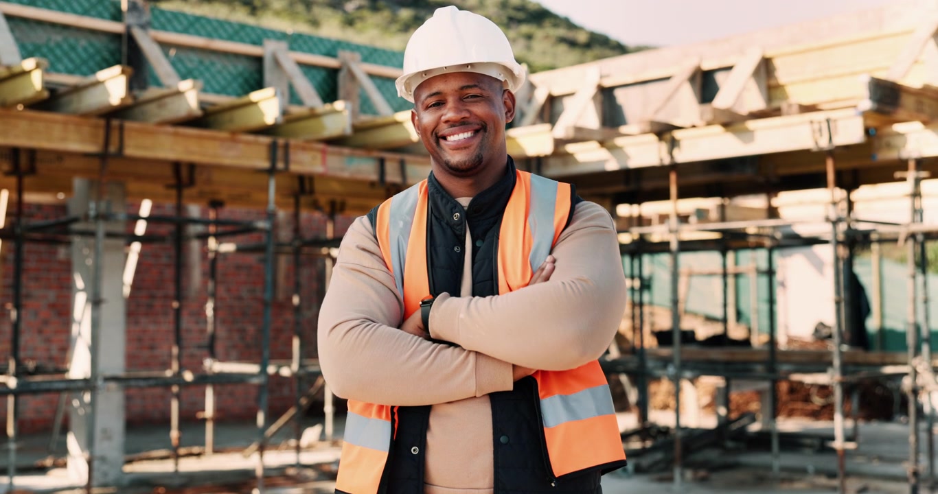 Smiling Construction Worker Putting On Hard Hat At Building Site