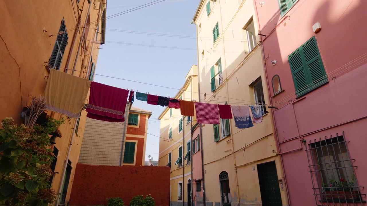 Bucato colorato che asciuga sui fili tra case tradizionali in un tranquillo vicolo di Genova