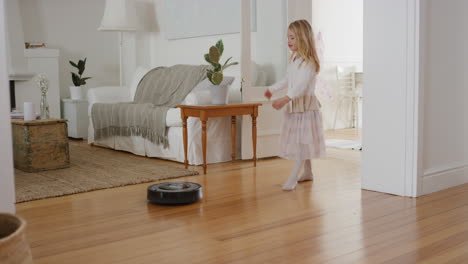 happy little girl dancing playfully with robot vacuum cleaner funny child pretending to be ballerina having fun playing dress up wearing fairy wings ballet costume at home 4k