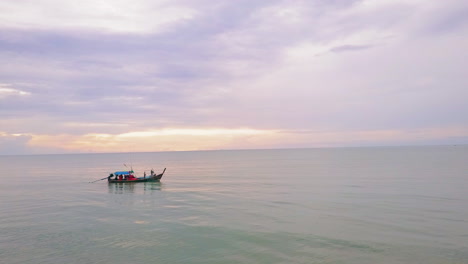 Vista-De-Drones-De-Un-Bote-De-Cola-Larga-En-El-Océano-Con-Una-Puesta-De-Sol-En-El-Fondo