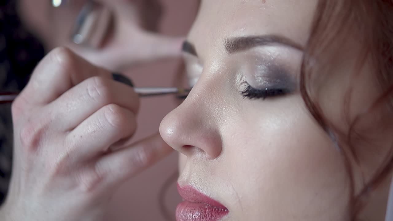 el maquillador pinta los ojos de la novia la mañana antes de la boda en close-up en cámara lenta