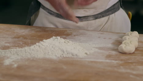 skilled baker shaping dough into buns with his hands