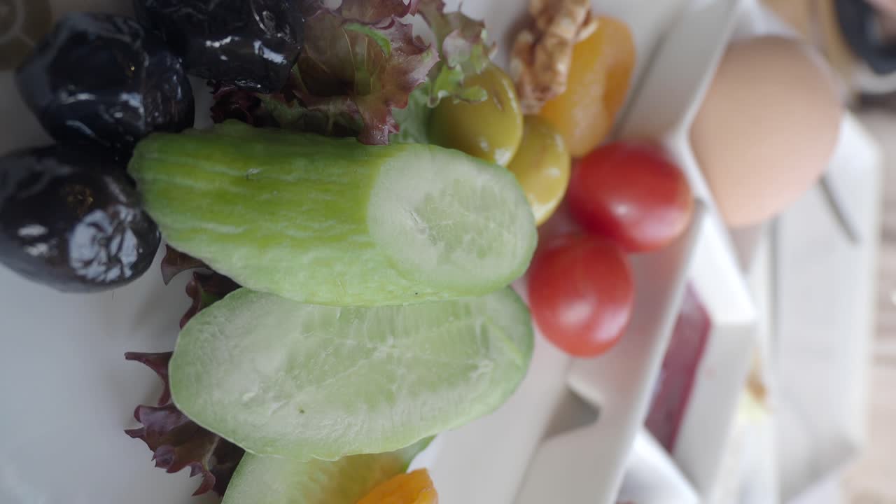 A healthy breakfast with fresh vegetables, olives, and egg