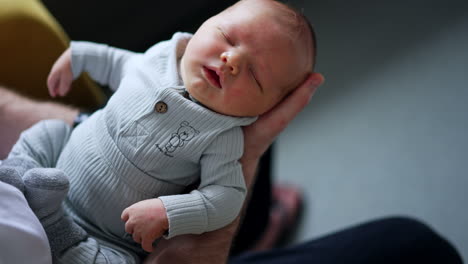 beautiful newborn baby sleeping on the parent's hand. tiny infant is swayed by a parent. top view close up.