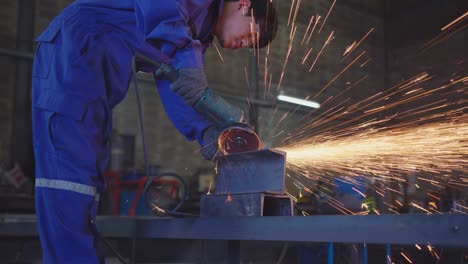 asian male technician worker in a safty uniform wear welders leathers,electric wheel grinding on steel structure in factory workshop in the garage, orange bokeh sparks fly to the sides