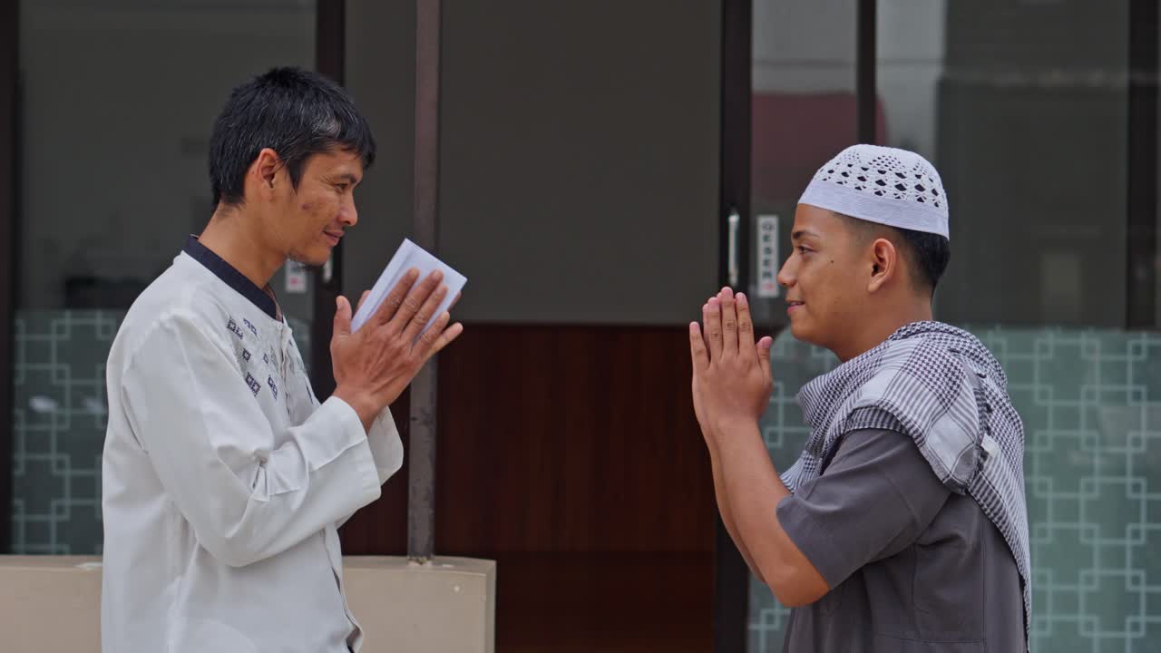 Pria Muslim mengenakan baju koko putih menerima amplop atau sumbangan dari guru agama