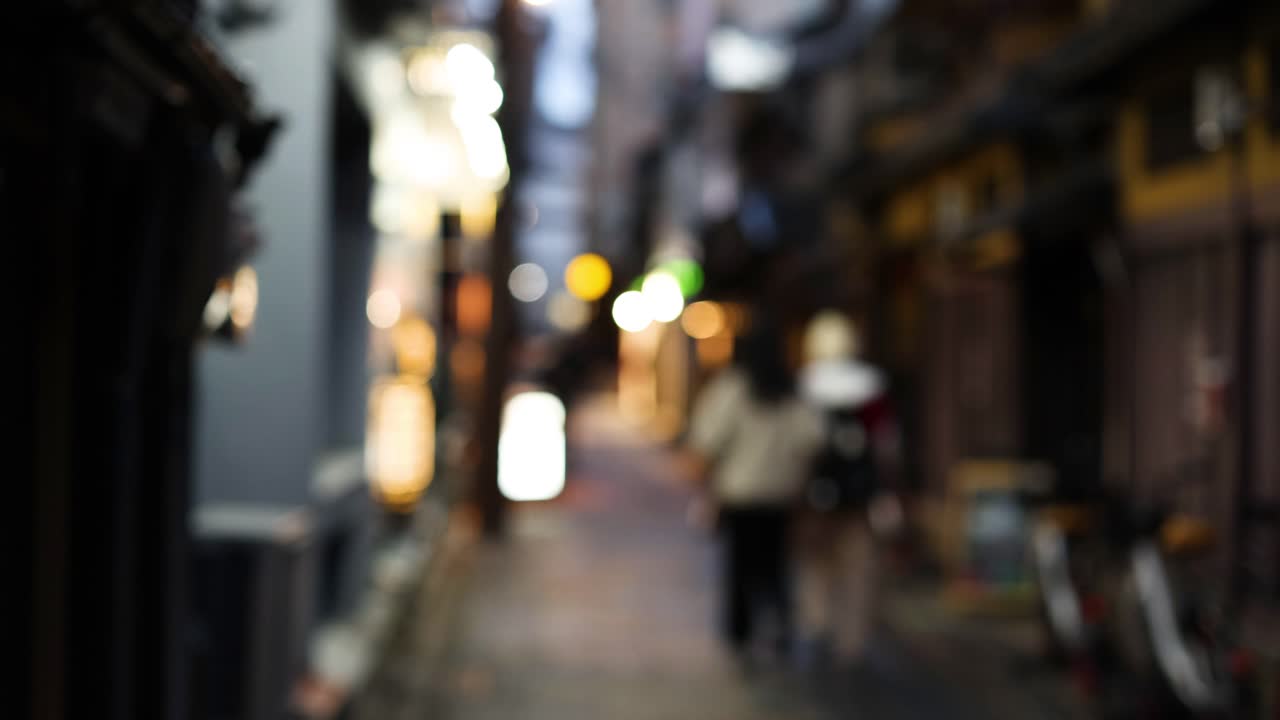 조명 된 골목길 을 고 있는 초점 이 벗어난 인물 들