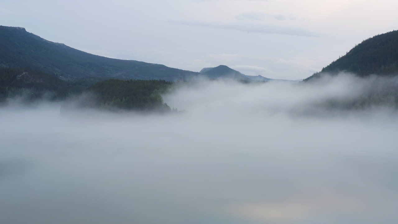 Flight over a foggy river. The mist is hanging low over the landscape creating a dark mystical mood over the whole scene.