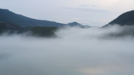flight over a foggy river. the mist is hanging low over the landscape creating a dark mystical mood over the whole scene.