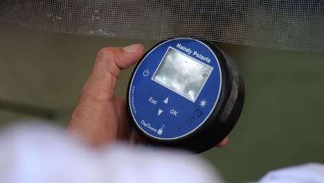 close up shot of workers hand holding a handy polaris to measure oxygen levels in a fish farming pond