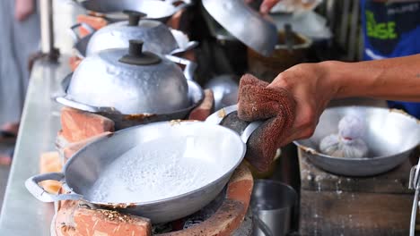 hands prepare coconut snacks on a street food stall in phuket, thailand. bright lighting highlights the traditional cooking process