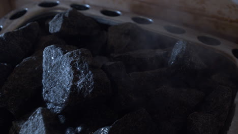 water pouring over steamy stove rocks in finnish sauna, close up shot