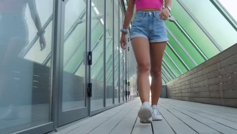 a young woman walking down a trendy covered boardwalk towards camera