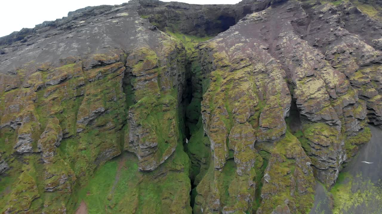 Aerial, reverse, drone shot away from the Raudfeldsgja gorge, on Botnsfjall mountain, cloudy day, in Snaefellsnes, Iceland