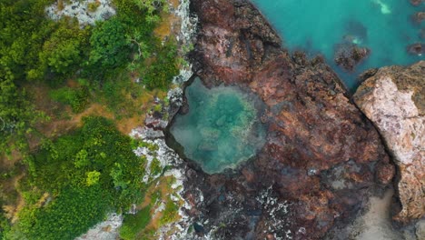 aerial: top down view of rock pool on small island surrounded by turquoise water