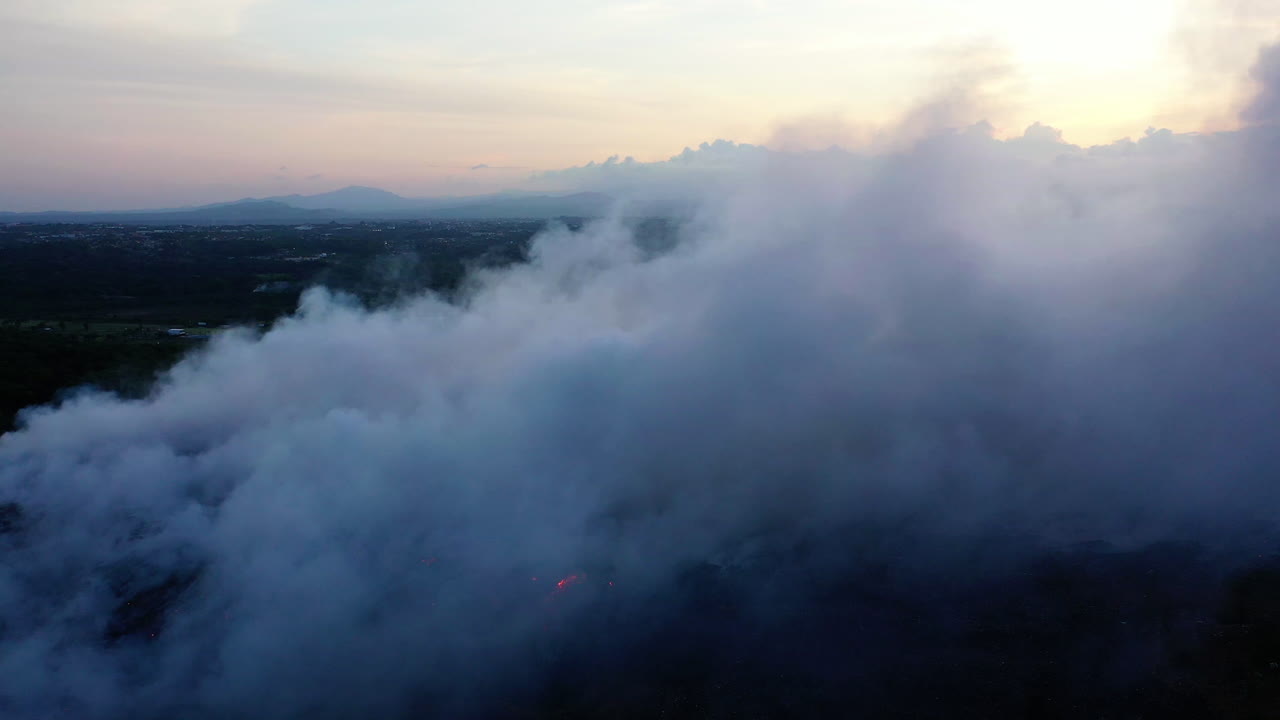 Aerial view of flames and a large smoke cloud, caused by the Californian wildfires, during sunset, in Los Angeles, California, USA - rising, pull back, drone shot
