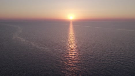 Aerial-view-of-boat-on-calm-sea-with-people-during-sunset,-Cefalu,-Sicily,-Italy