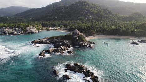 drone flying backward from wilderness coastal landscape from tayrona national park, colombia