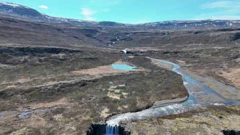 Cascada-De-Fossfjordur-Con-Pájaro-Volando-Hacia-La-Cámara-En-El-Oeste-De-Islandia---Retroceso-Aéreo