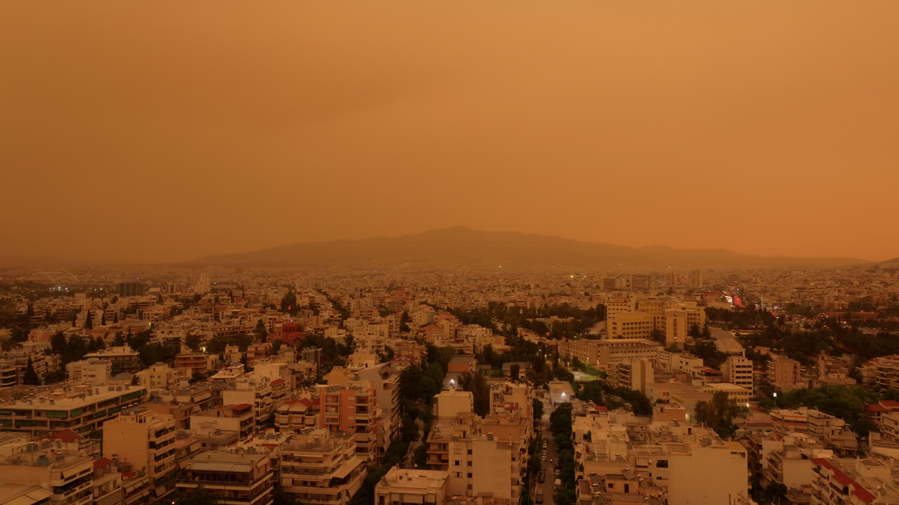 Aerial establishing of Sahara dust storm over Athens, blanketing streets and rooftops in haze