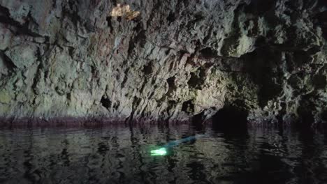 Mysterious-scene-inside-a-sea-cave-with-a-beam-of-light-coming-down-from-the-ceiling-and-reflecting-on-a-wall,-Vis-island,-Adriatic-Sea,-Croatia