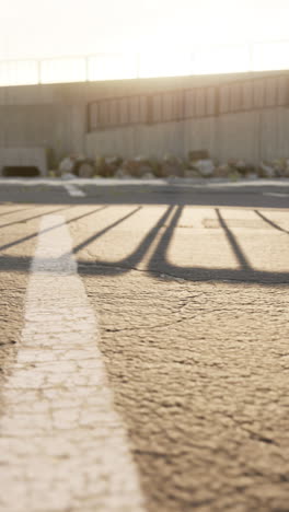 a close-up shot of the shadow of a fence on the ground in a parking lot