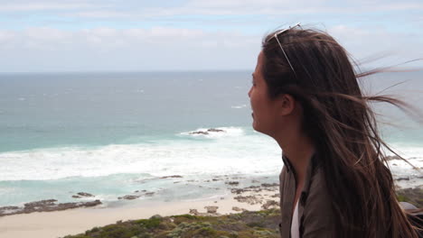 linda chica morena en la playa en australia señalando con el dedo el océano