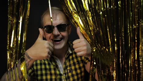 Portrait-of-caucasian-man-posing-on-black-background.-Gold-shining-foil-strips.-Party,-music,-disco