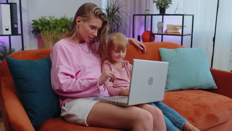 niña hija divirtiéndose con la madre o la niñera disfrutando usando computadora portátil pc ver dibujos animados en casa