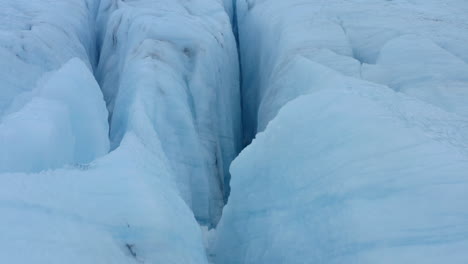 Toma-Aérea-Lenta-Mirando-Profundas-Grietas-En-Un-Espeso-Glaciar-De-Hielo